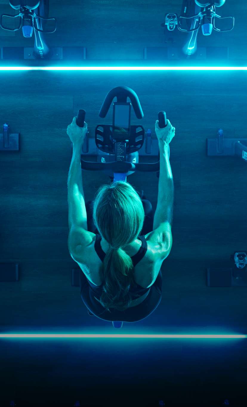 Overhead view of a woman pedaling a stationary bike in a cycle class