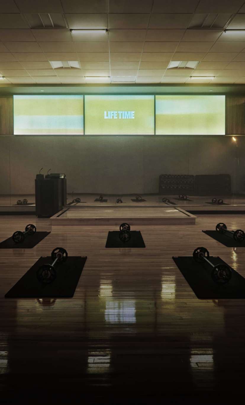 A dimly lit fitness studio with yoga mats and weights