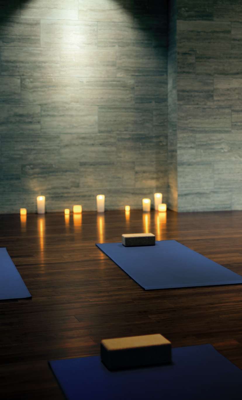 A dimly lit fitness studio with yoga mats and candles creating ambiance