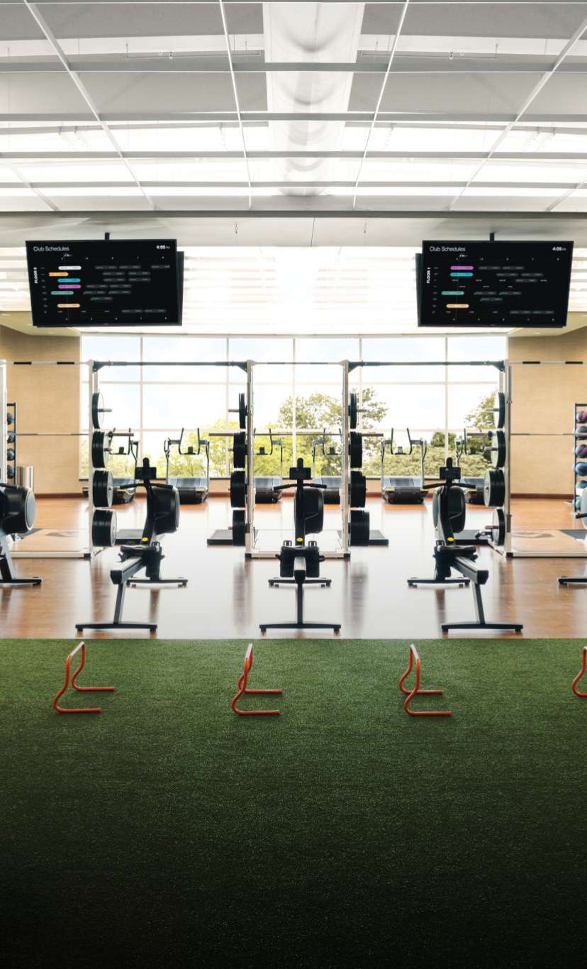 An indoor turf area surrounded by workout machines and TVs