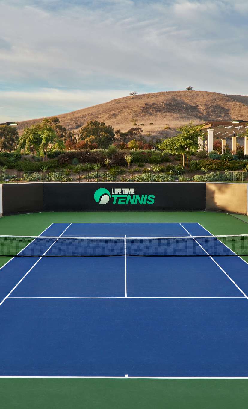 An outdoor tennis court with mountains in the distance