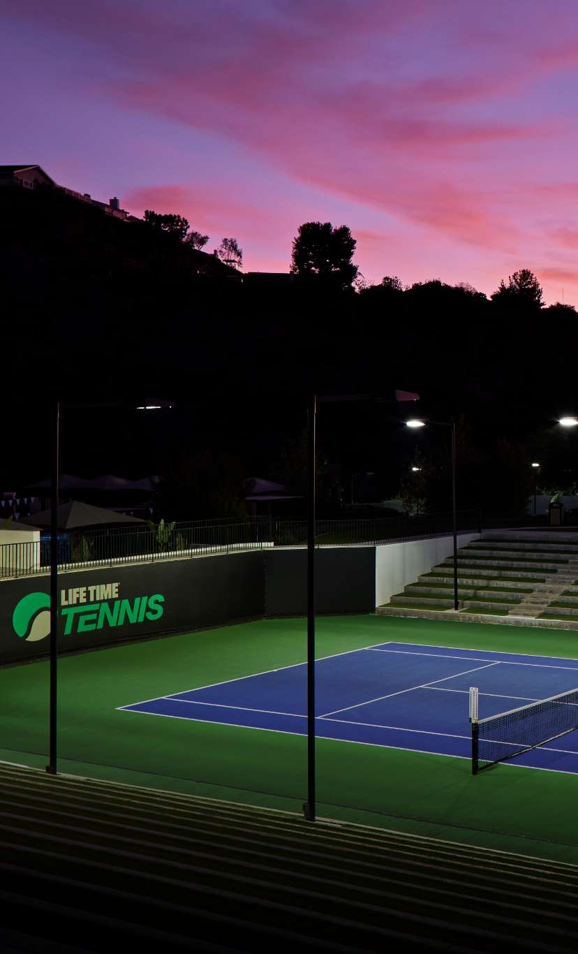 An outdoor tennis court at dusk