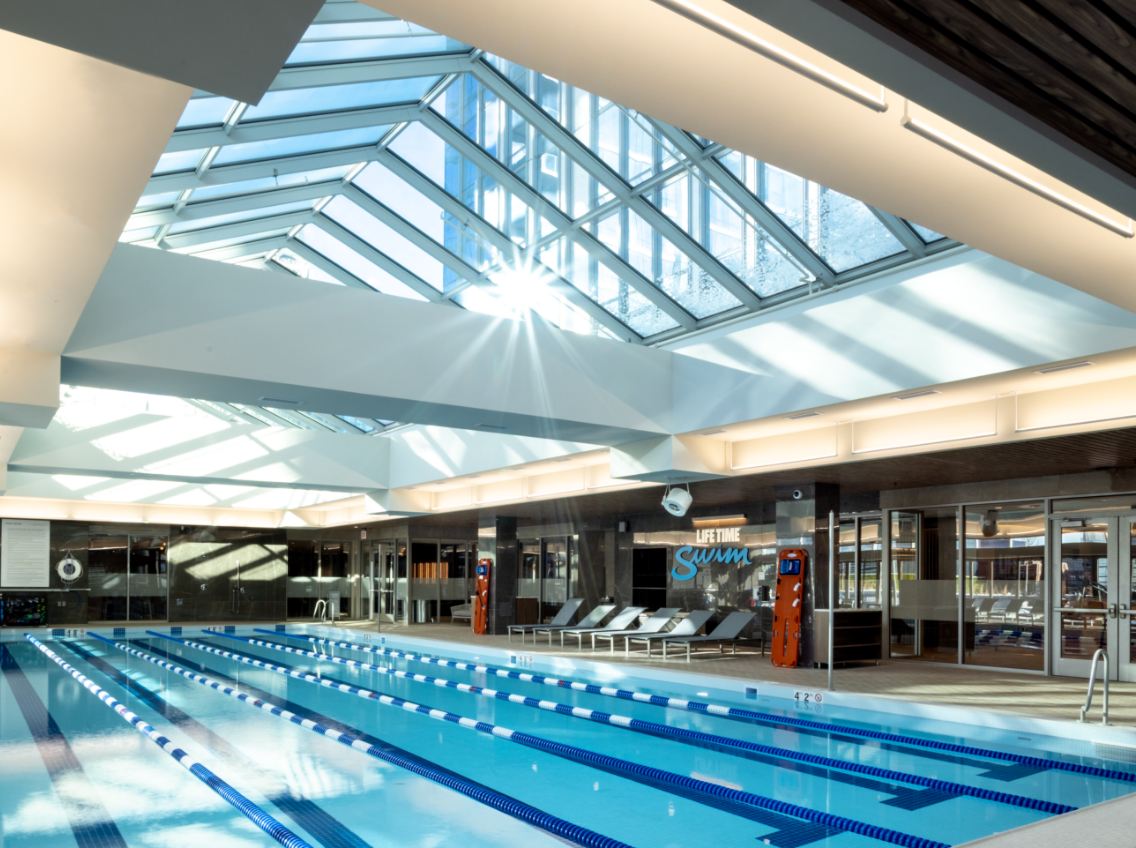 The lap pool with sun shining through overhead windows at Life Time River North at One Chicago