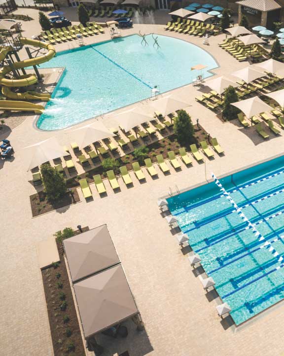 an aerial view of the outdoor pool deck with lap pool, leisure pool, deck chairs and water slide