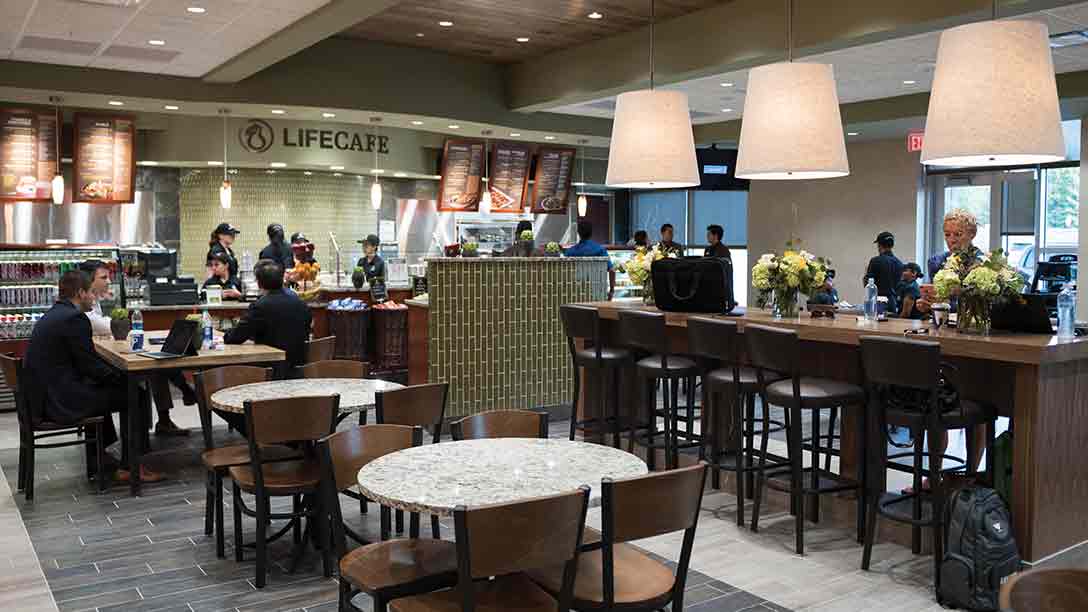Tables in a LifeCafe, with coolers for healthy foods in the background