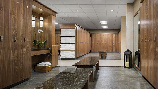 View of Life Time's luxurious locker rooms, wood lockers, marble benches, and towels.