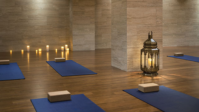 A yoga studio, with candles, lanterns, yoga mats and yoga blocks laid out.