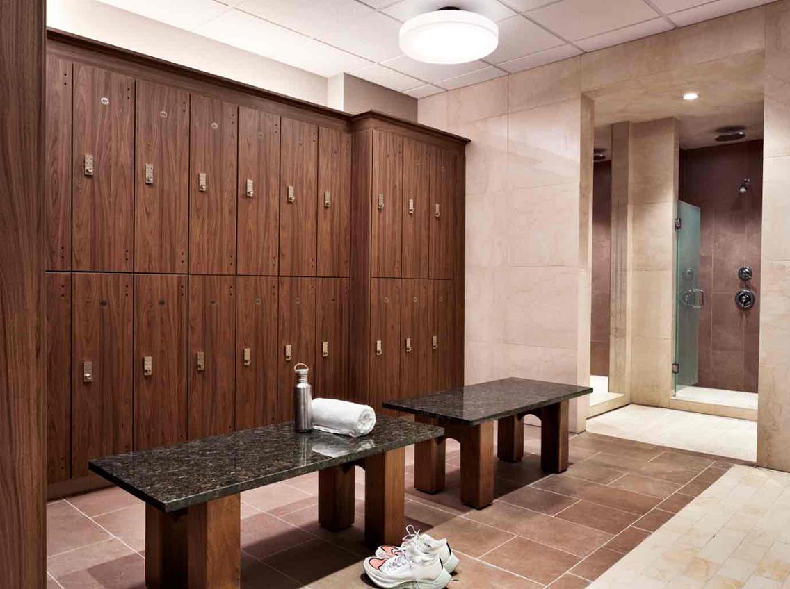 Lockers, bench, and shower area in the locker room at Life Time Battery Park.