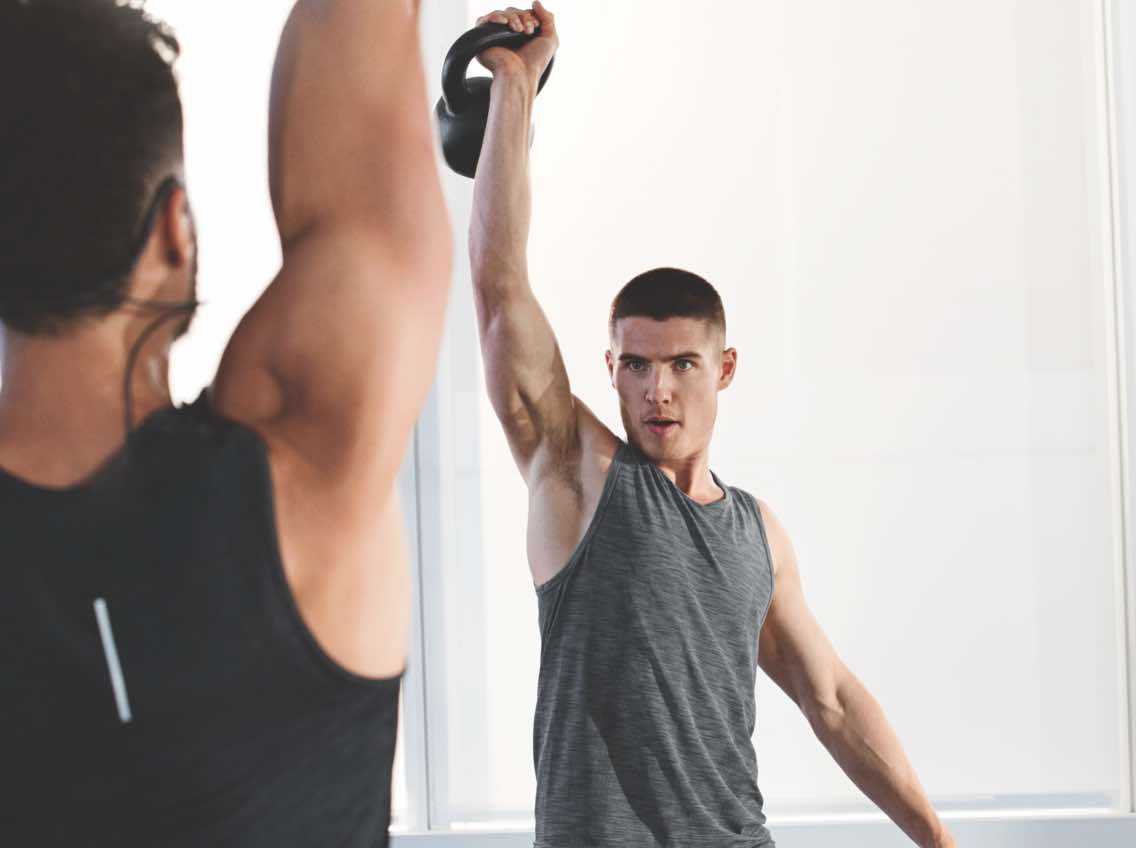 Man and fitness instructor working out with kettlebells