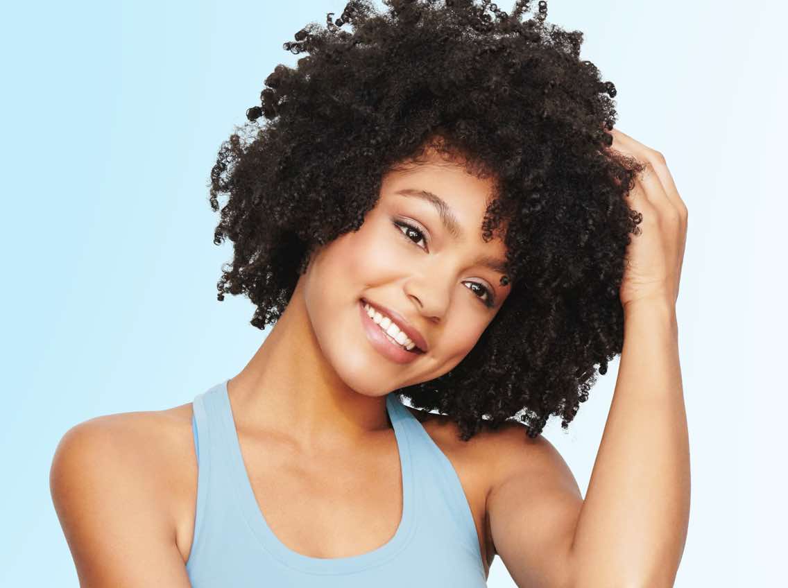 Smiling woman with dark, course, curly hair
