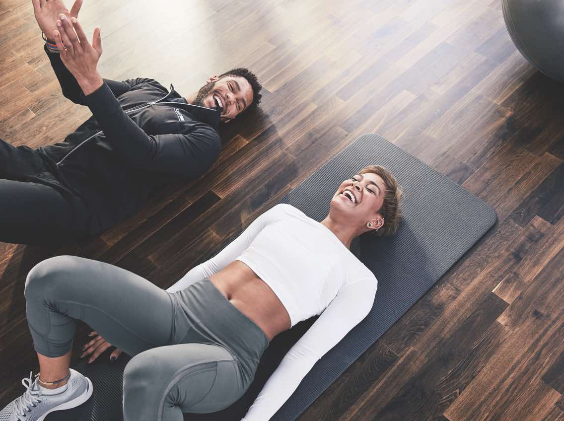 Woman and Personal Trainer lying on yoga mats at Life Time