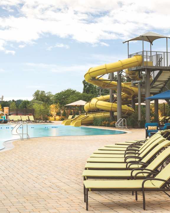 Outdoor pool area at Life Time with rows of lounge chairs and waterslide