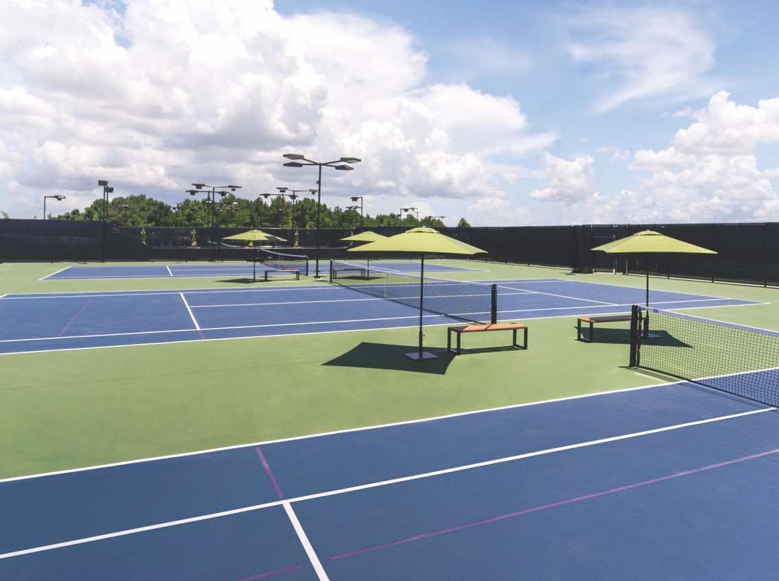 Seating areas with umbrella tables on the outdoor tennis courts at Life Time