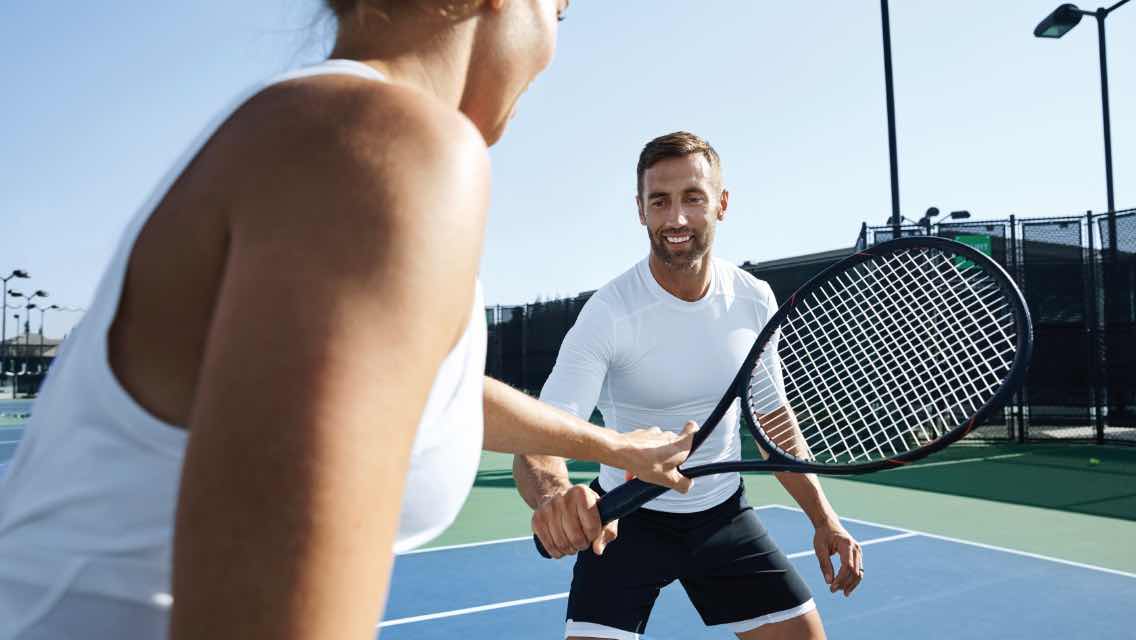 Man and woman taking tennis lessons at Life Time.