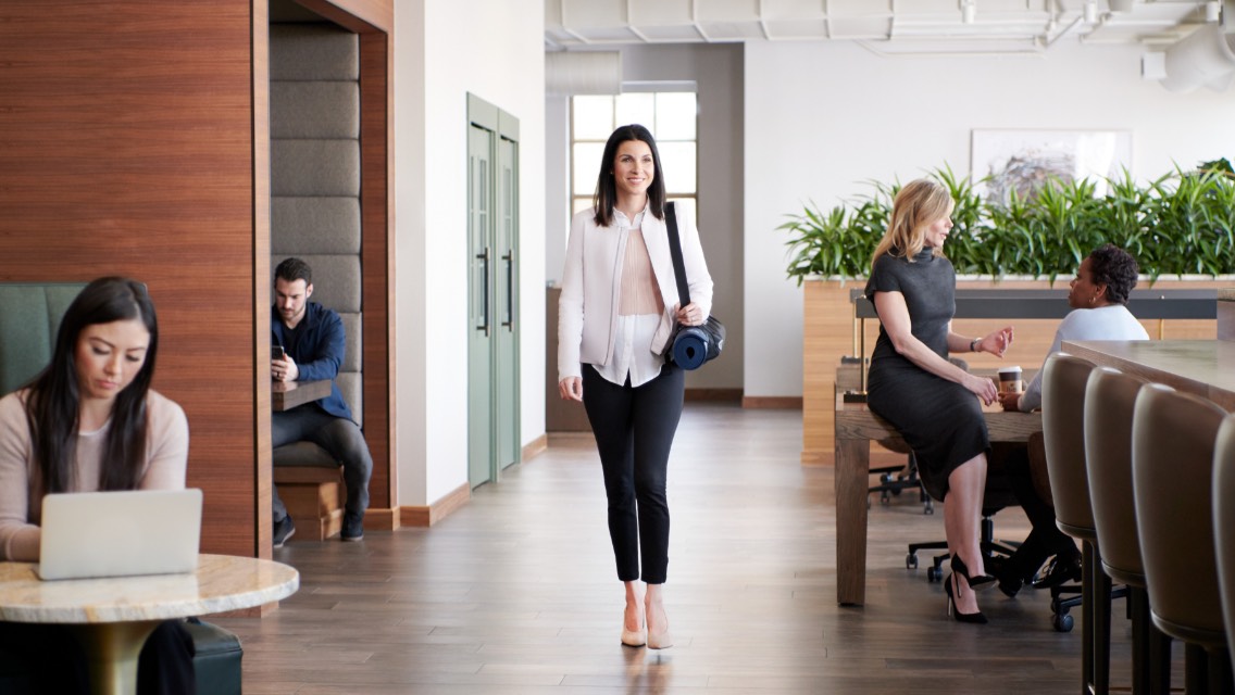 Woman walking inside and smiling at a Life Time Work