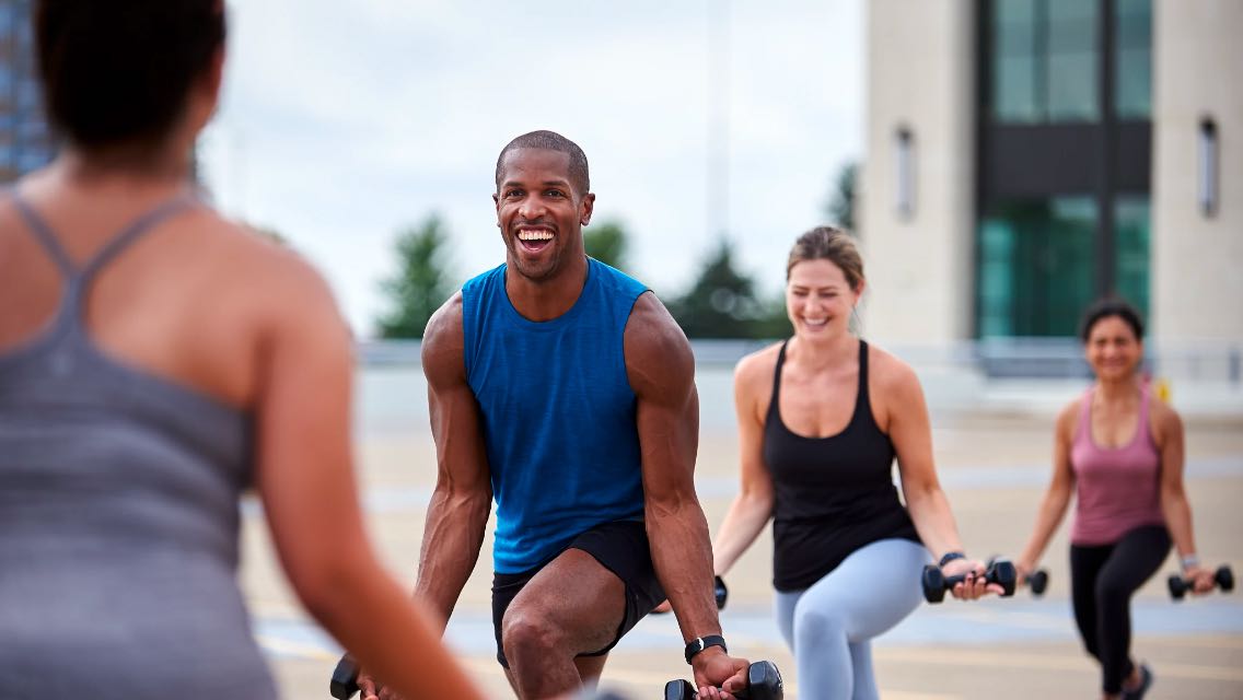 A man in a blue shirt doing an outdoor group training class at Life Time