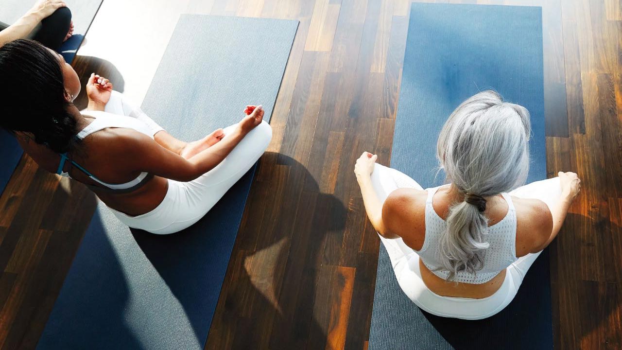 Overhead shot of two woman meditating on yoga mats.