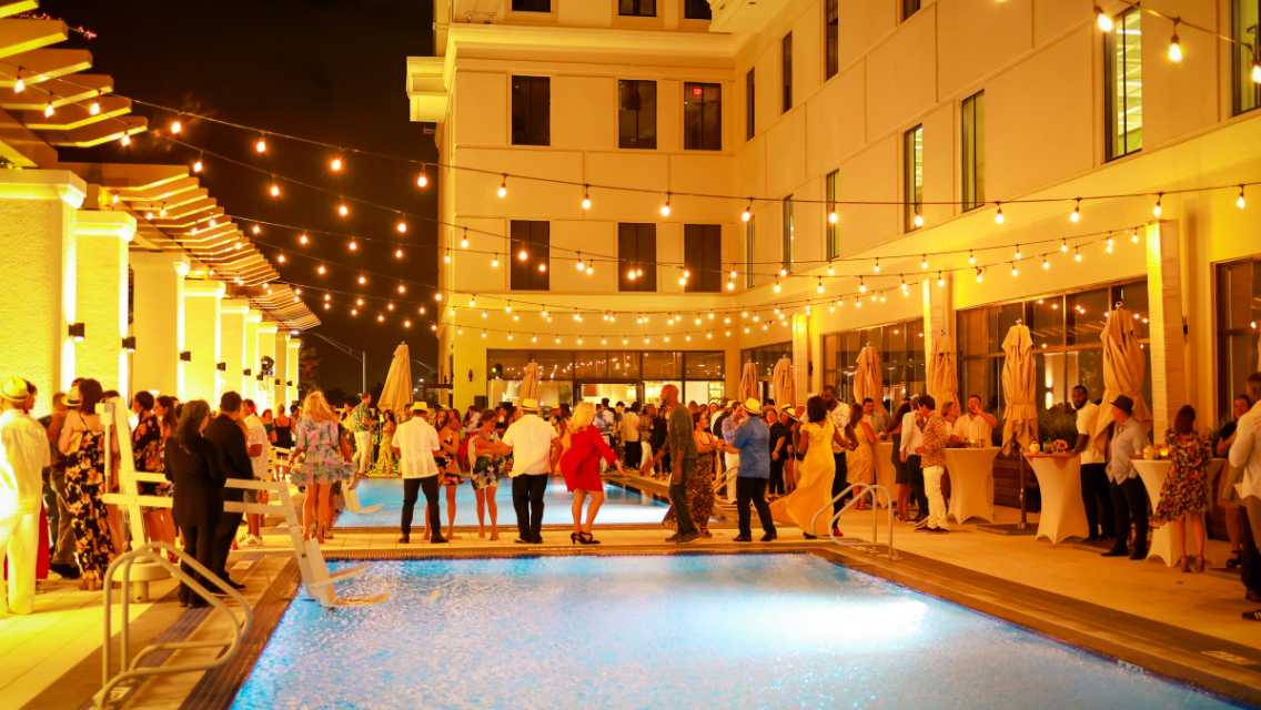 People enjoying music and beverages at night on the outdoor pool deck at Life Time