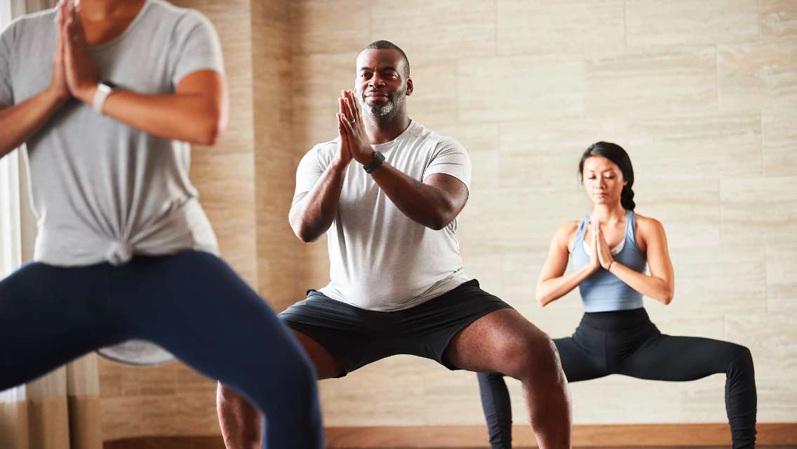 Three people in a class studio practicing yoga. 