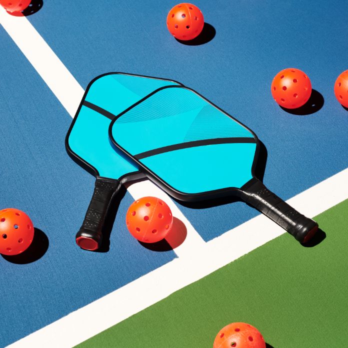 pickleball paddles and pickleballs laid on a pickleball court