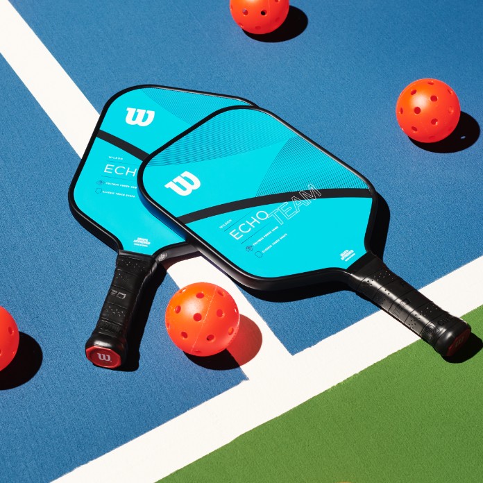 pickleball paddles and pickleballs laid on a pickleball court