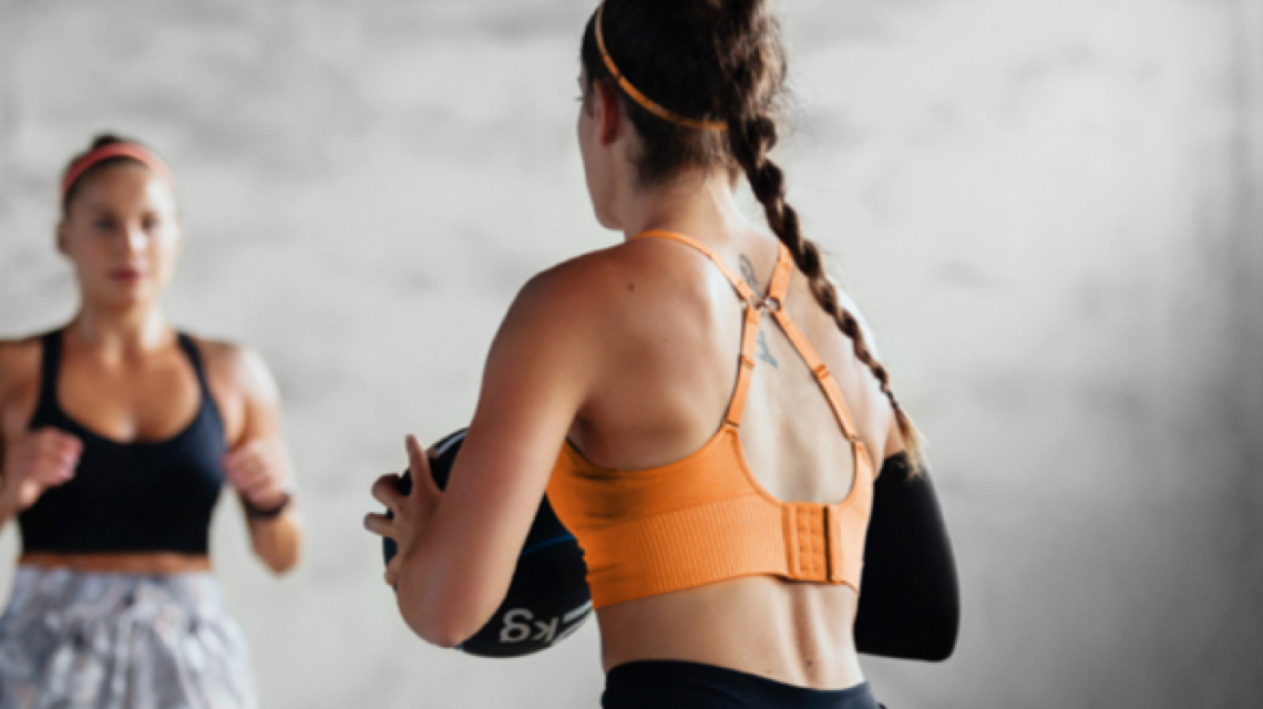 A couple of women passing a medicine ball in their group training class