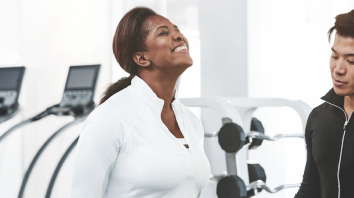 A woman smiles enthusiastically while working with a trainer