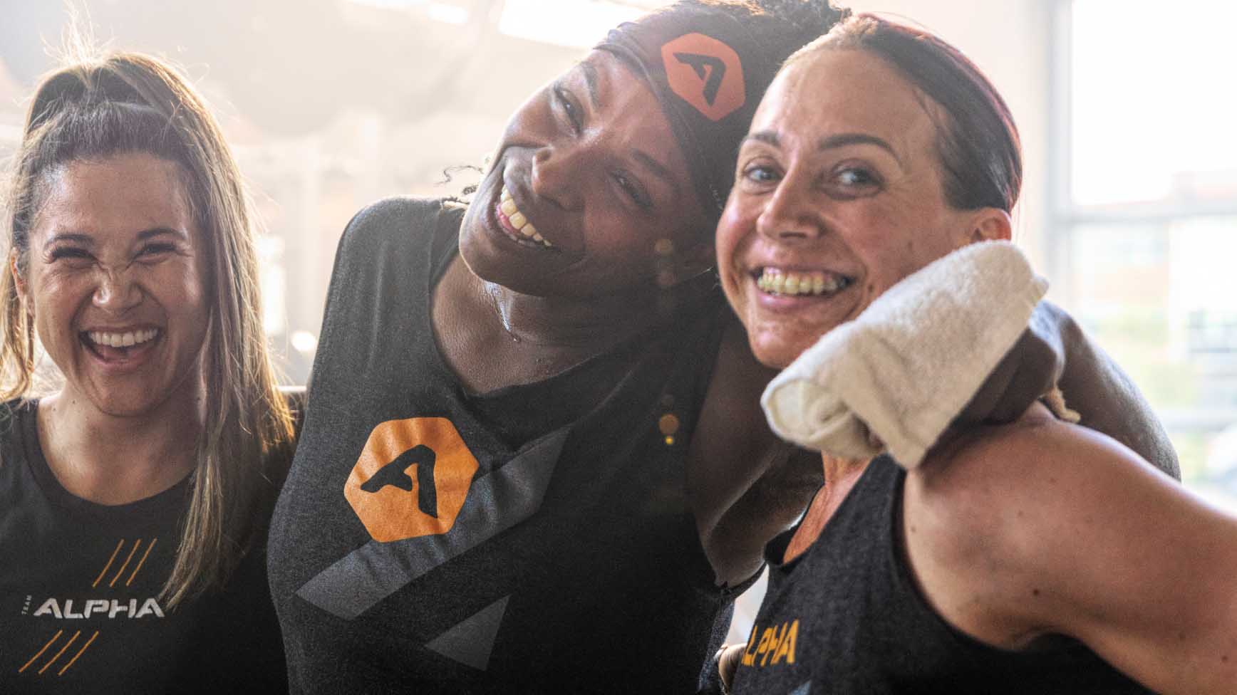 three girls smiling wearing alpha life time apparel