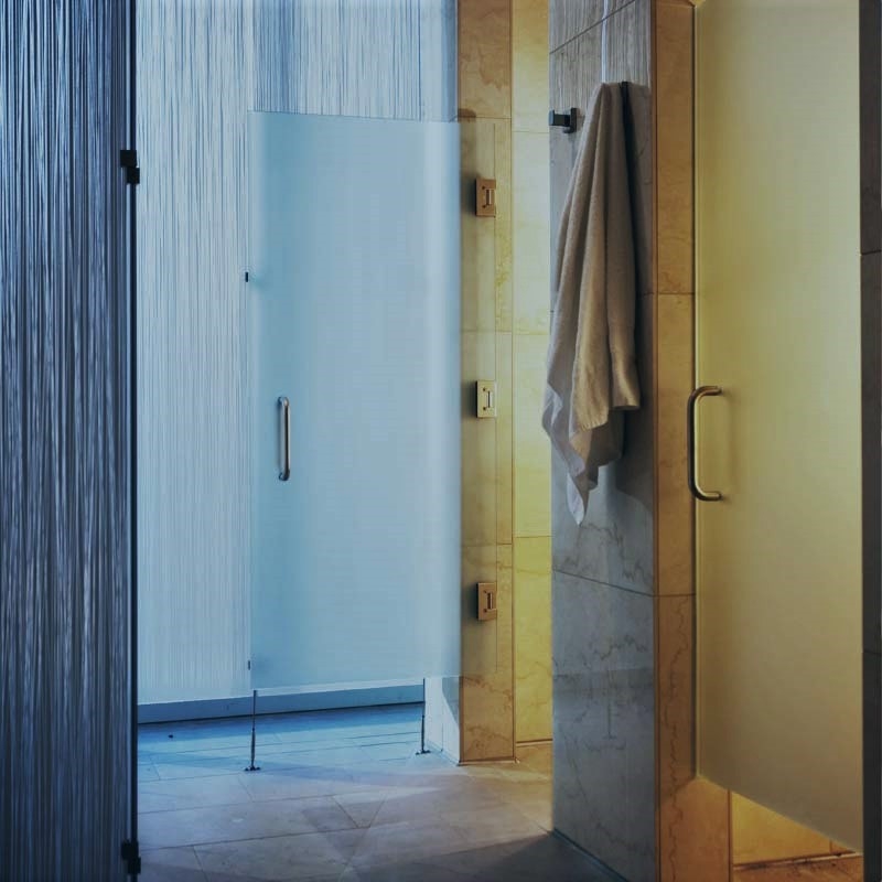 A towel hangs outside a marble and glass shower stall