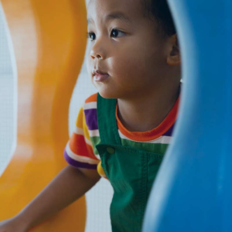 A toddler boy plays on play equipment in the Kids Academy