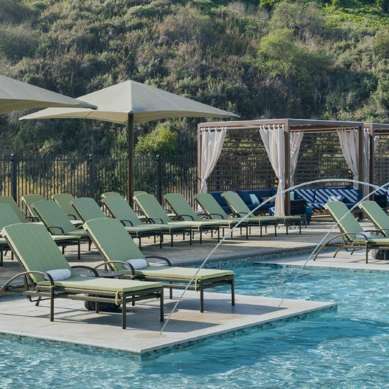 Rows of lounge chairs, cabanas, and umbrellas surround a gleaming outdoor pool