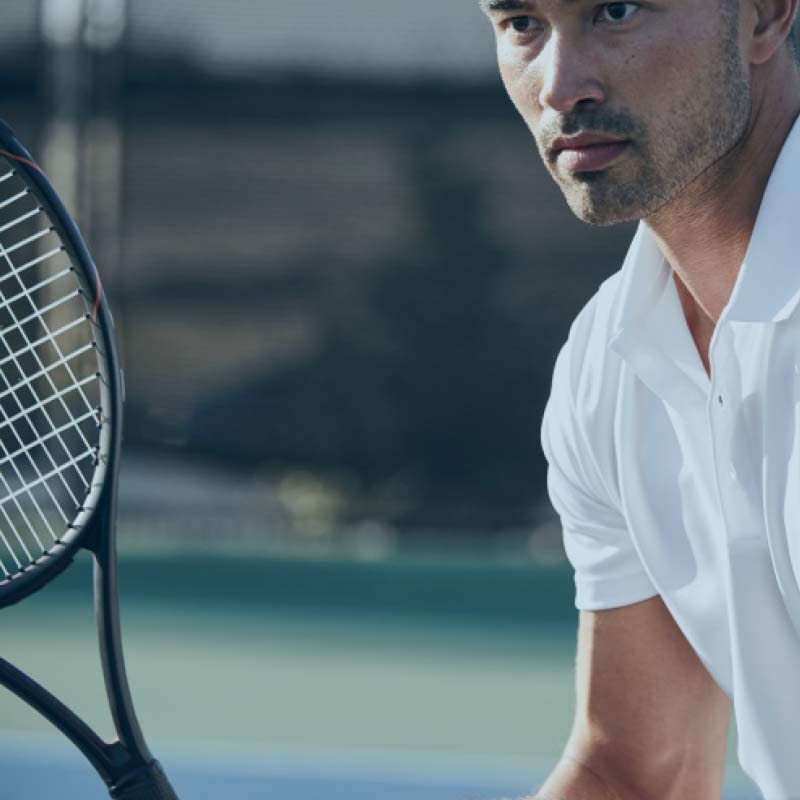 A close up view of a man holding his tennis racquet