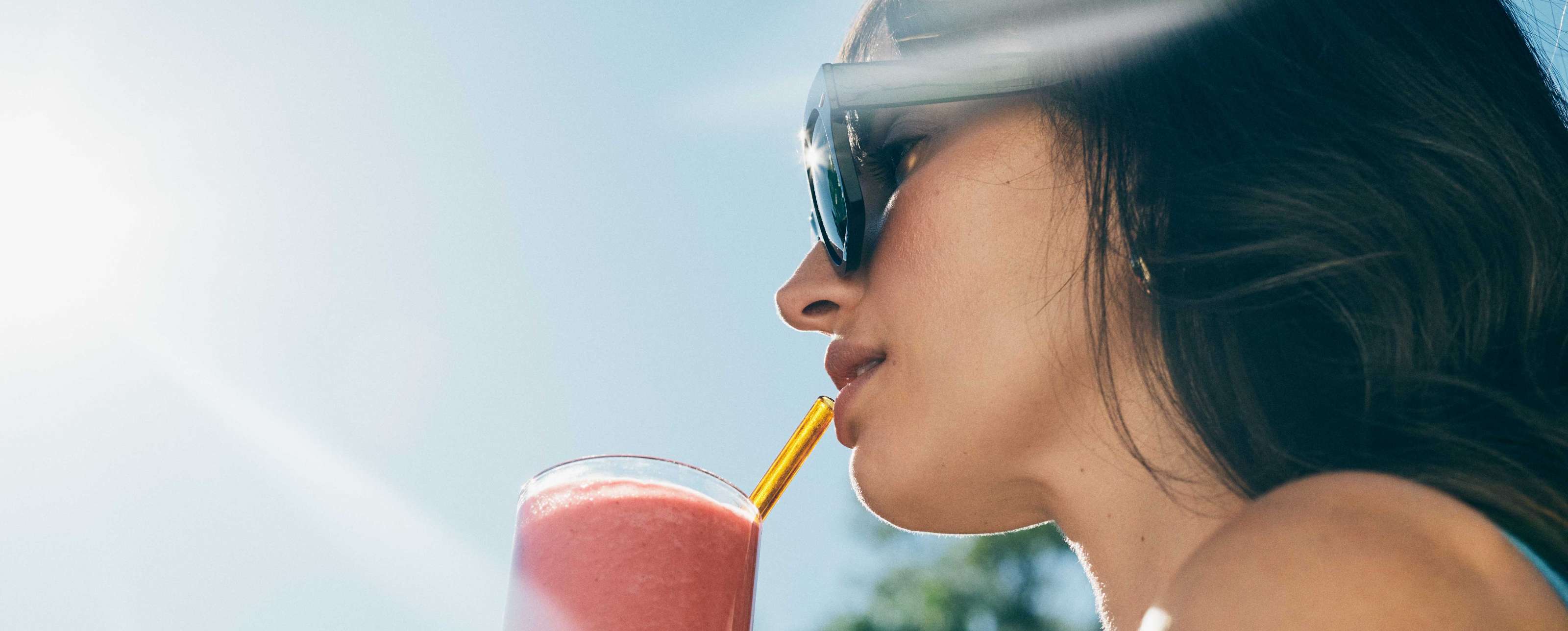 a woman sips on a smoothie in the bight sunshine