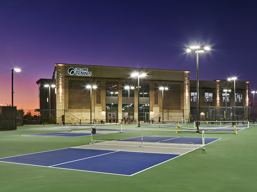 A Life Time club with outdoor pickleball courts at dusk