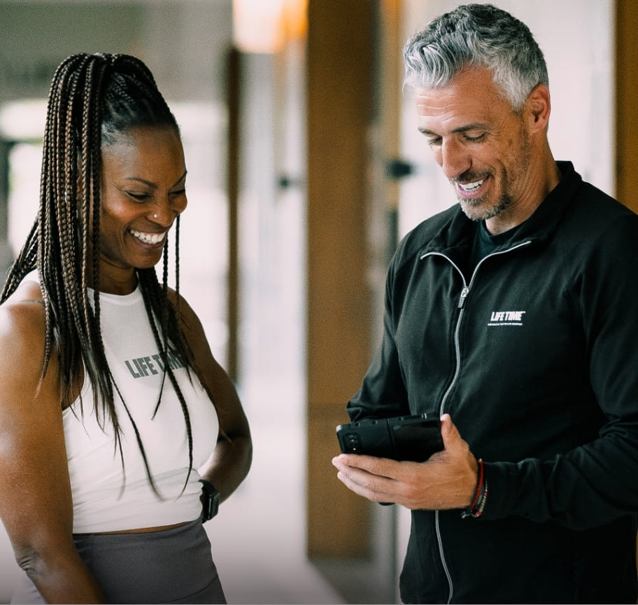 A male trainer and his new training client complete an intake consultation. The trainer records the woman's answers on an iPad, which he will use to create a custom training plan.