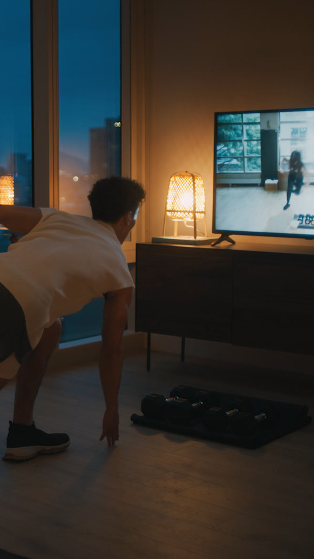 A man follows a workout playing on his tv in his living room