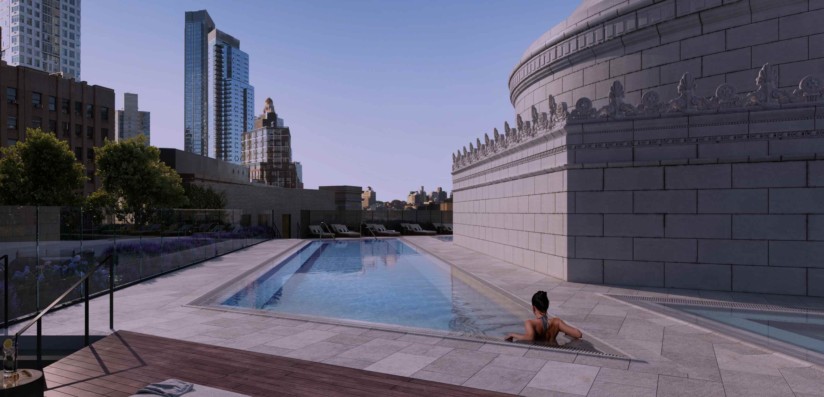 A woman sitting in an outdoor pool looking over the city view