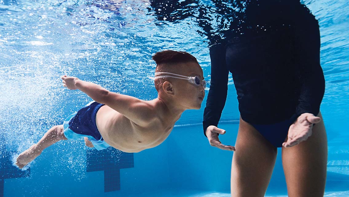 Young boy swimming under water with goggles