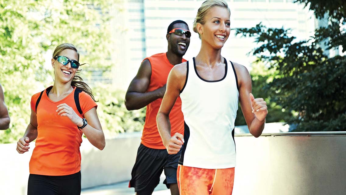 3 runners rounding a corner during an outdoor run, all dressed in Life Time run gear