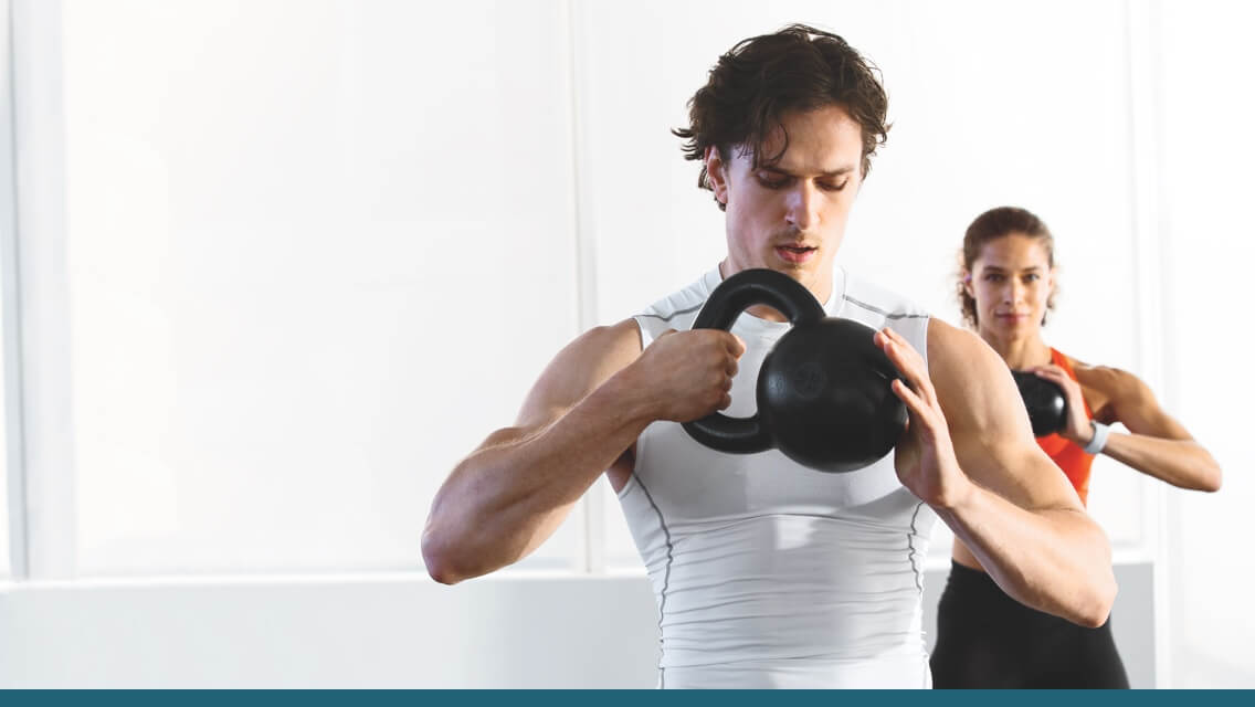 A man and woman lifting kettlebells