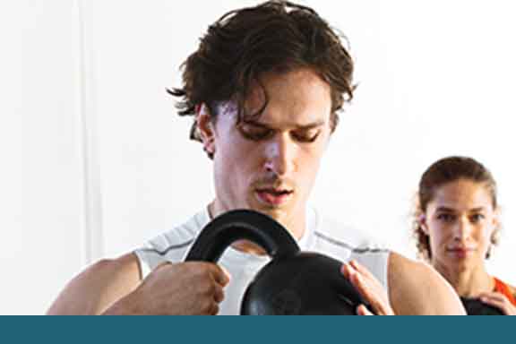 A man and woman lifting kettlebells