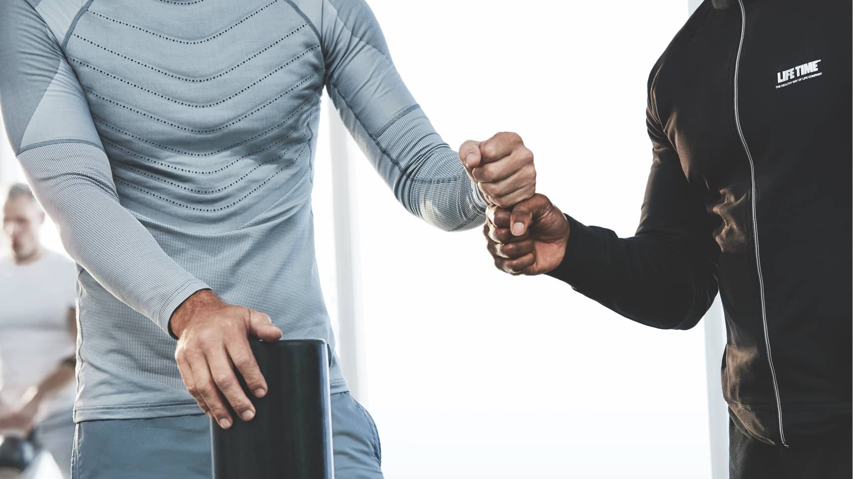 A trainer and his client share a fist bump during a workout