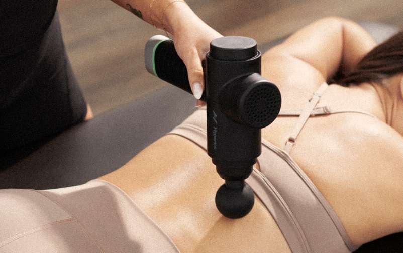 Woman sitting laying down while a trainer uses a massage tool