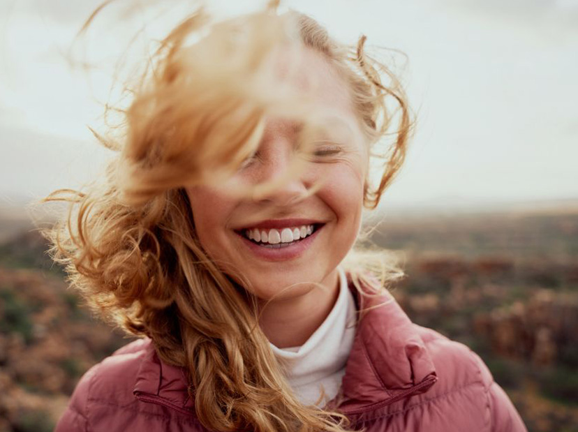 girl with red hair smiling as her hair blows in the wind