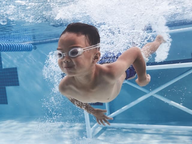 a yound boy swims underwater